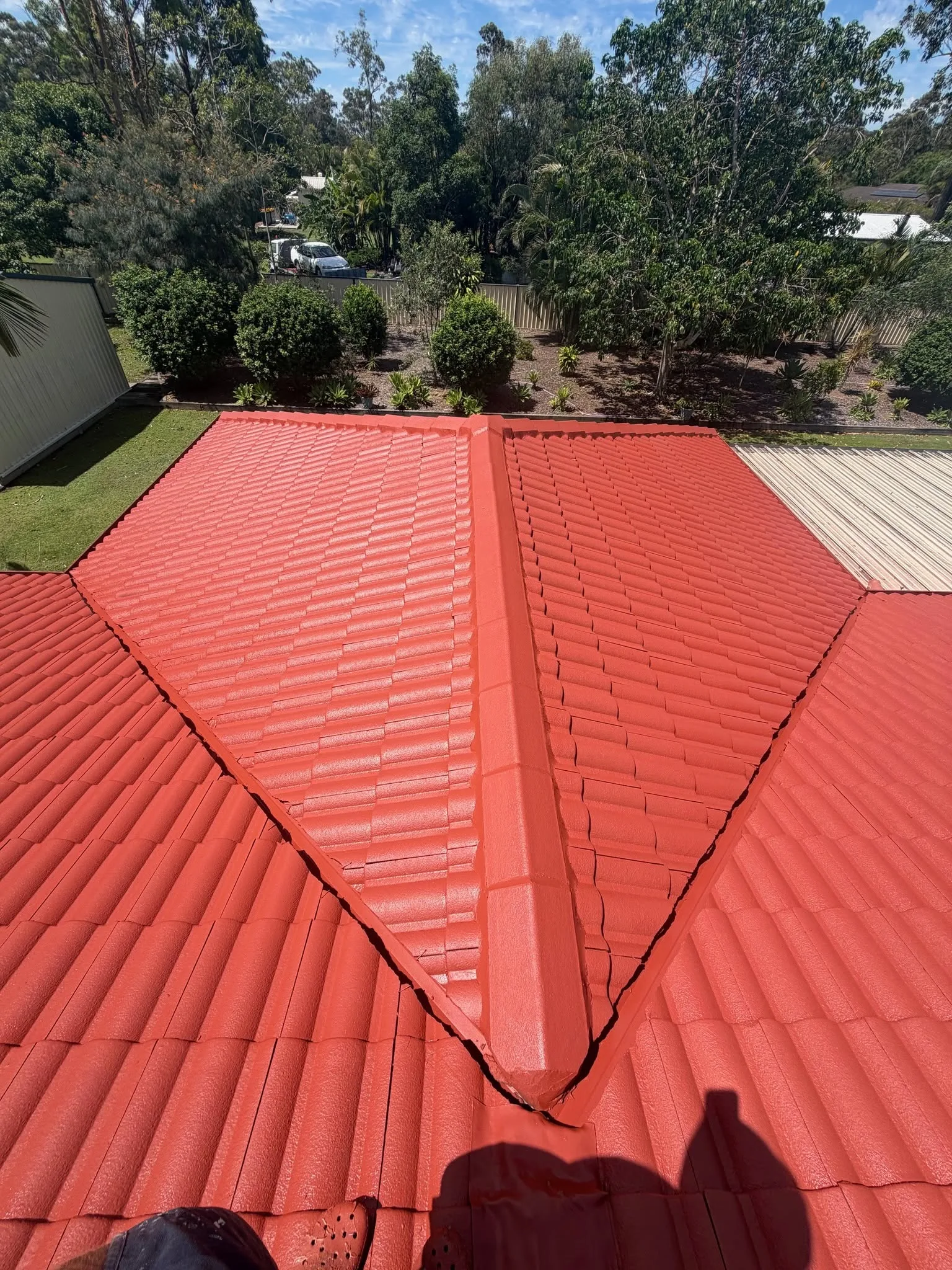 Close aerial view of a freshly painted Manor Red tile roof valley on a home surrounded by trees