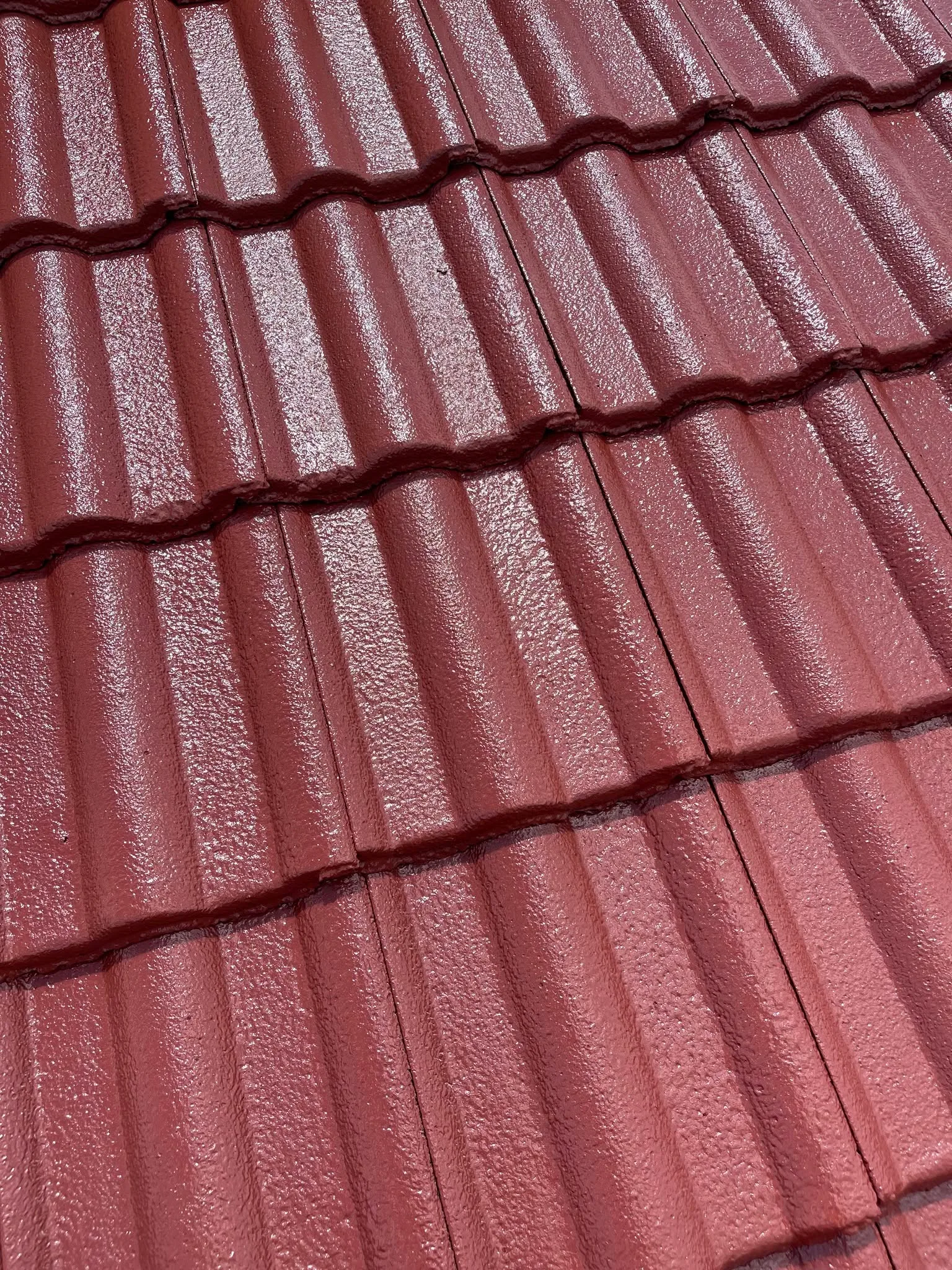 Close-up texture shot of freshly painted deep red tile roofing
