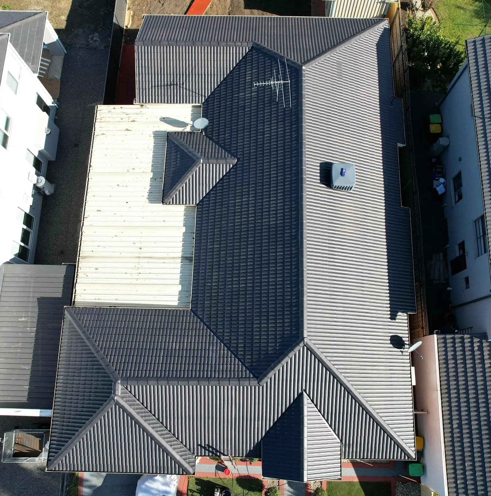 Straight-down aerial view of a large restored tile roof on a substantial home, showing the full roof layout among neighbouring properties
